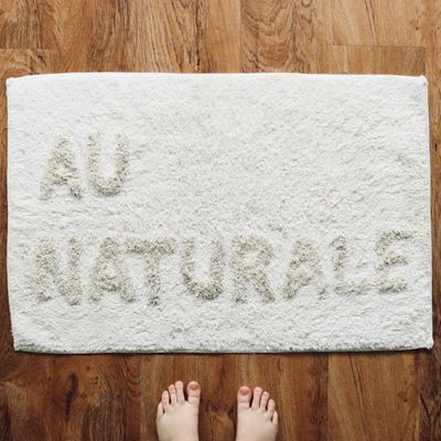 Bare feet on a simple exercise mat on a wooden floor.